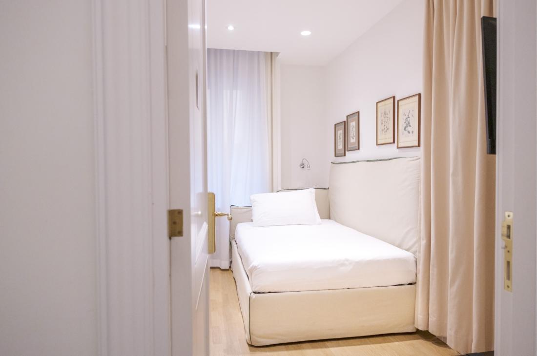 Camera accogliente con letto bianco, pareti chiare e quadri eleganti.