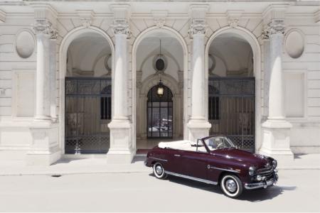 Auto d'epoca elegante davanti a un palazzo storico, atmosfera di lusso e nostalgia.