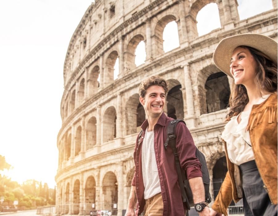 Coppia felice cammina mano nella mano davanti al Colosseo al tramonto.